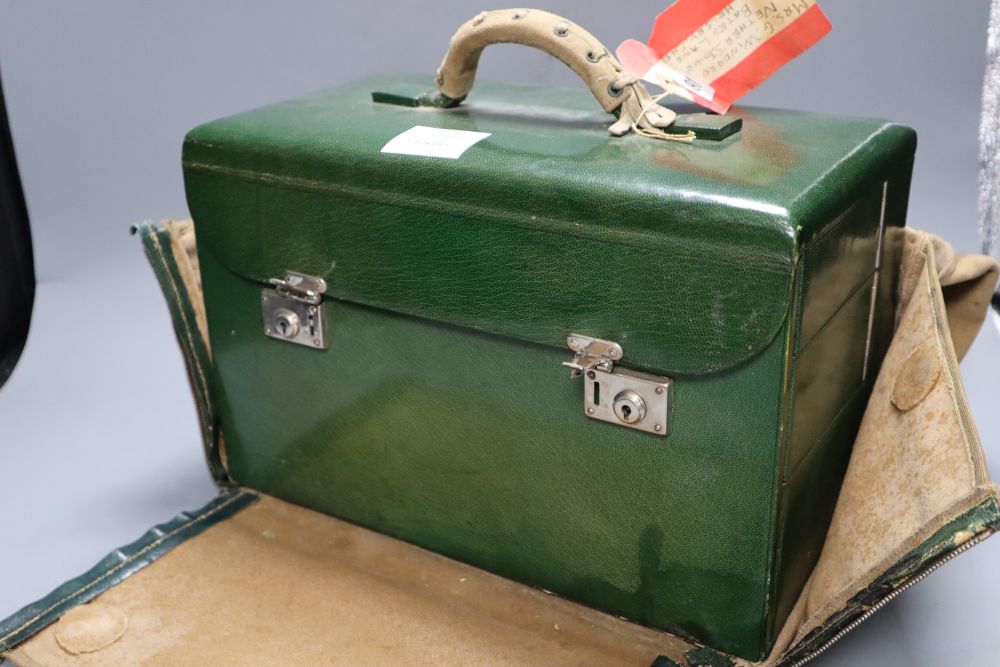 A 1930s ladies green leather travelling toilet case, fittings include seven glass and enamelled bottles, 32cm, in original travelling